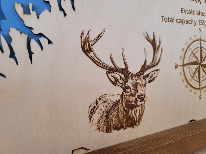 Close up of laser-engraved wood map of Island Park Reservoir featuring engraved elk wildlife and compass rose