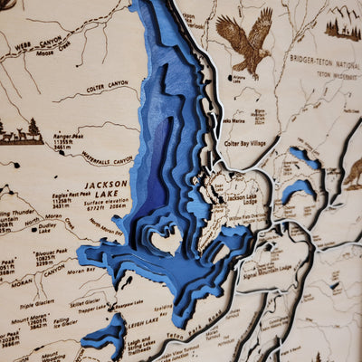 Close up of Grand Teton National Park wooden map featuring blue water inlay, wildlife, trail names, and other landmarks