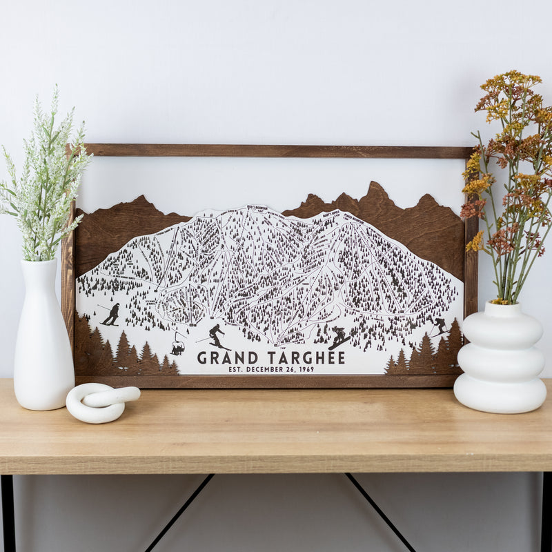 Wooden ski map of Grand Targhee with engraved trails and mountain silhouette, displayed on a shelf.