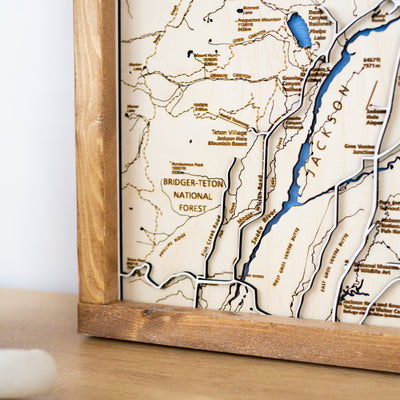 Close up of Grand Teton National Park wooden map bottom left corner featuring wildlife, trail names, Snake River, and other landmarks