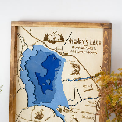 Close-up of Henry's Lake laser-engraved wood map featuring a title, elevation, wildlife, and blue water inlay