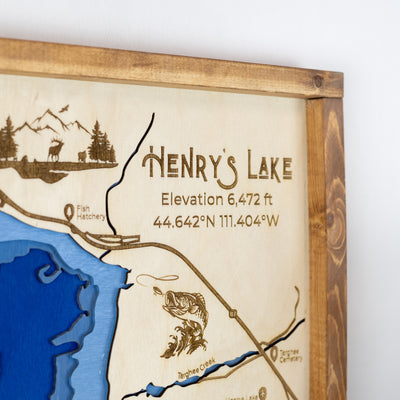 Close-up of top right corner of Henry's Lake laser-engraved wood map featuring a title, elevation, wildlife, and blue water inlay