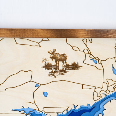 Close up of laser-engraved wood map of Island Park Reservoir featuring engraved moose wildlife and streets surrounding the lake
